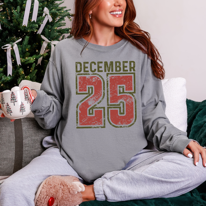 Person wearing a gray sweatshirt with 'December 25' print, sitting in front of a decorated Christmas tree.