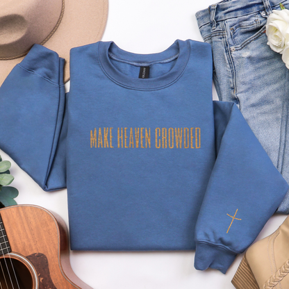 Blue sweatshirt with 'MAKE HEAVEN CROWDED' text, surrounded by jeans, a hat, and a guitar on a white background.