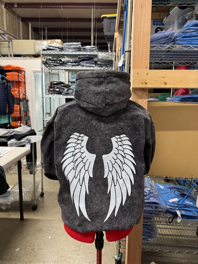 Gray hoodie with white wings on a mannequin in a warehouse setting